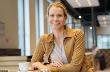 Smilende kvinne som sitter på cafe og studerer