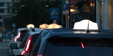 Taxier står parkert på rad langs en gate om kvelden.