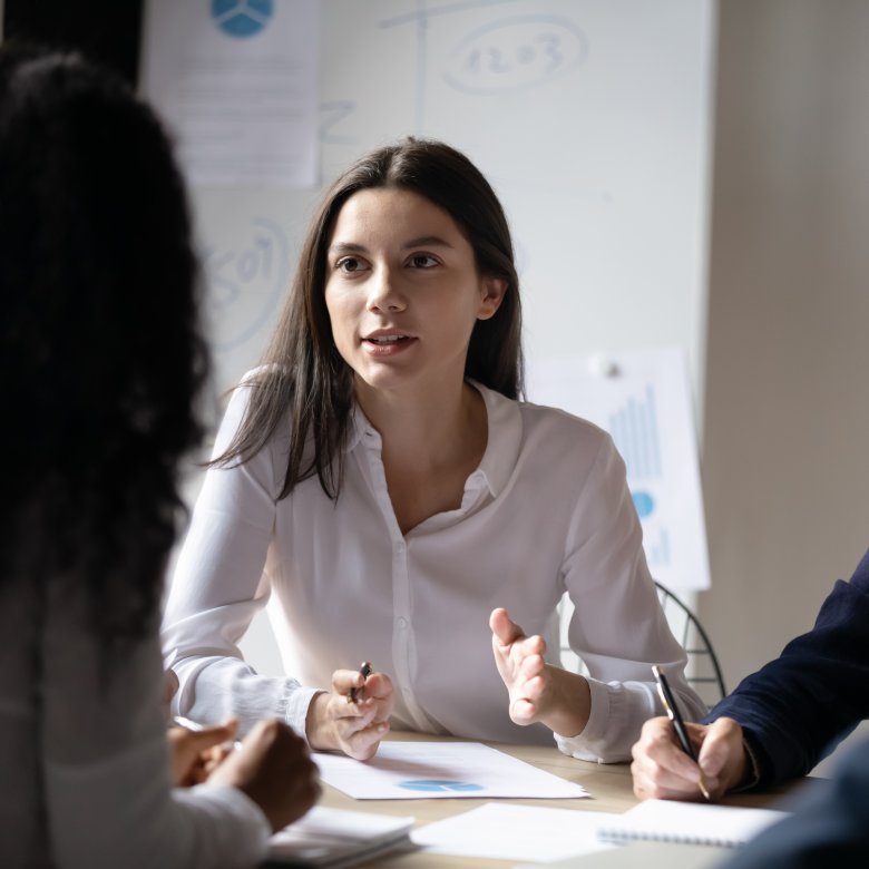 Tre kvinner diskuterer energioptimalisering og bærekraft i et møte.