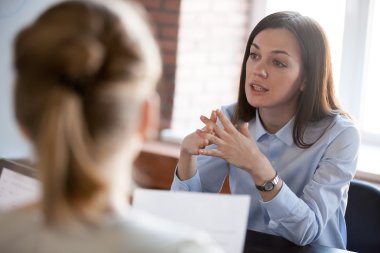 To kvinner i samtale på et kontor, en med dokumenter i hånden.