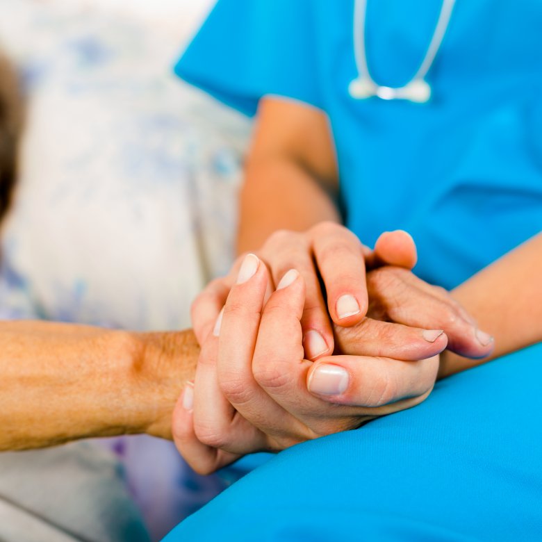 helsepersonell holder hånden til en pasient
